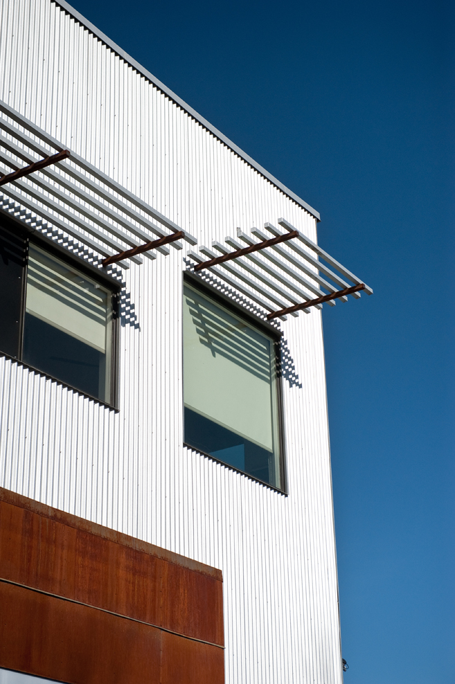 Upper facade detail of the Vonmod building with corrugated metal panels and steel sunshades in Denver