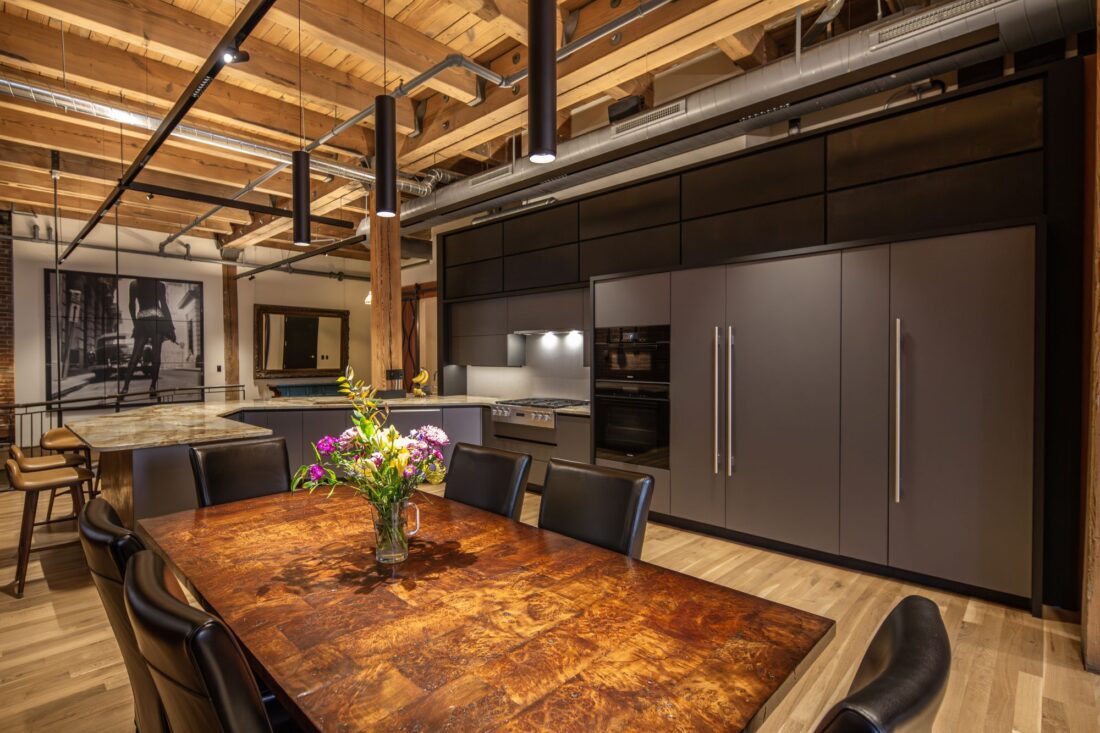 Metallic grey kitchen cabinetry viewed from dining area with integrated appliances in Denver residence