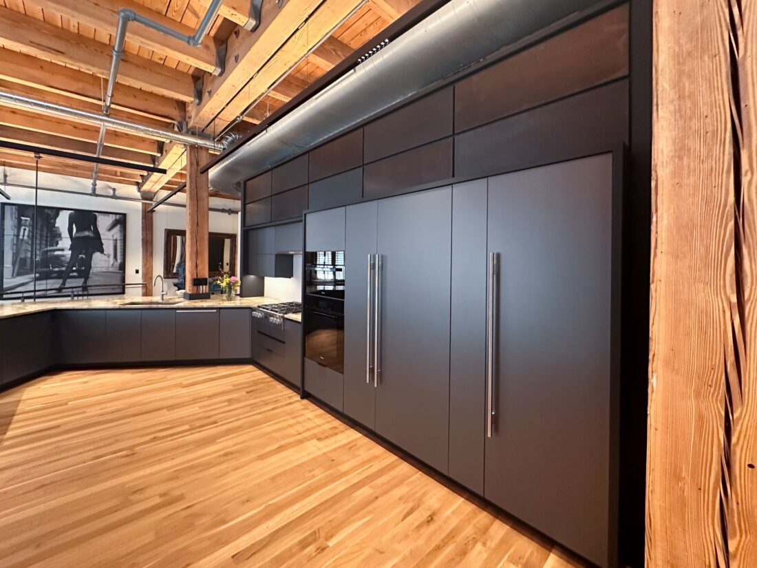 Full-height metallic grey kitchen cabinetry with integrated refrigerator panels in Denver condo