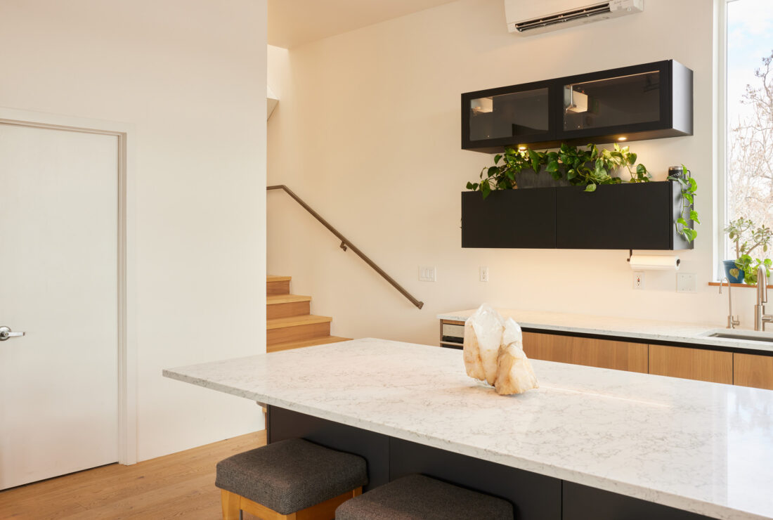 Modern kitchen island with Nero Ingo cabinetry, frozen walnut accents, and Arrigoni wood flooring