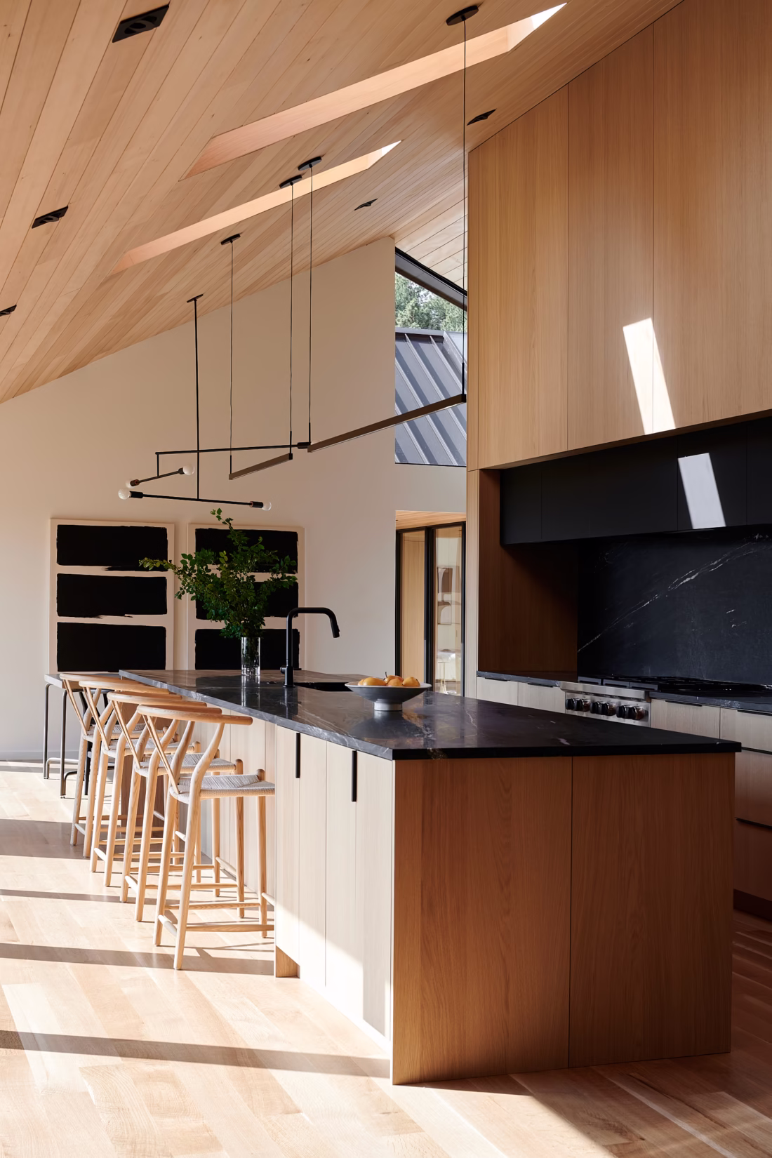 Ivory oak kitchen with long island, integrated seating, and dark stone countertop in Boulder home