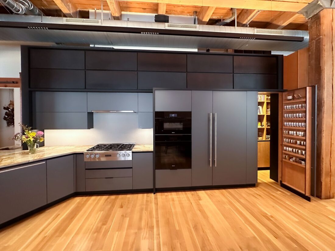 Metallic grey kitchen cabinetry with integrated appliances and full-height storage in Denver condo